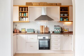 Et køkken med hvide skabe, en Bosch ovn og et flisebeklædt backsplash.
