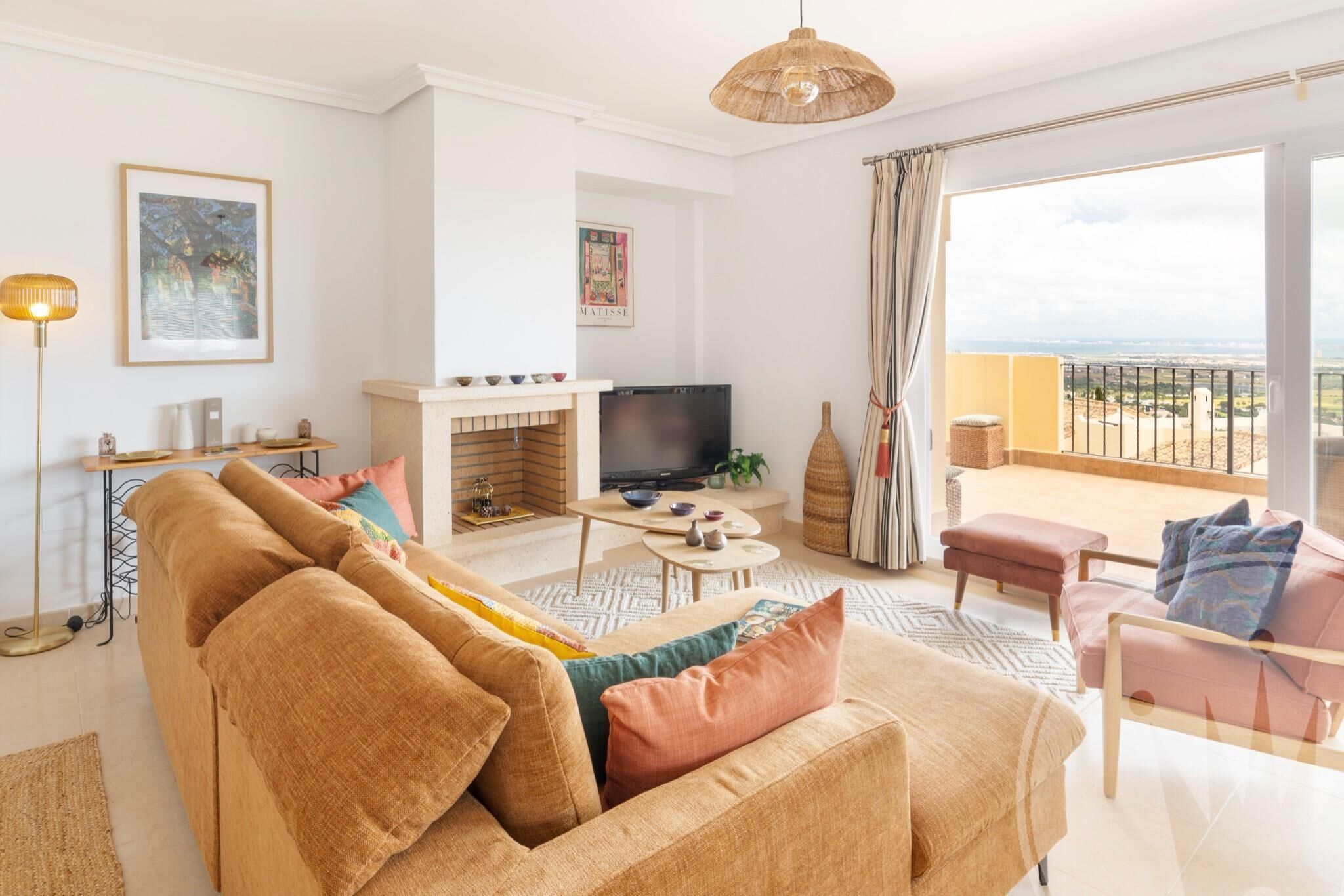 Ein modernes Wohnzimmer mit Sofa, Fernseher und Blick auf einen Balkon.