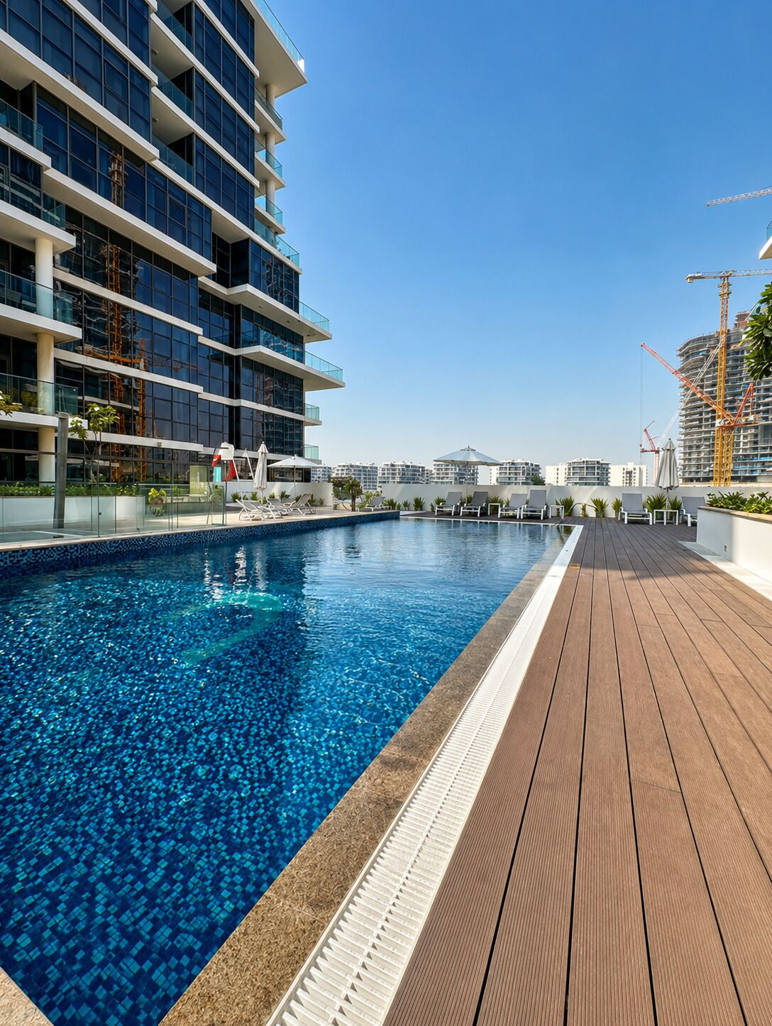 A modern building with a swimming pool and a wooden deck.