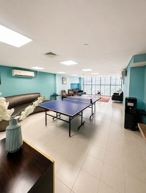 A room with a ping pong table, a sofa, and a coffee table. - Pure Voyage Damac Hills (Dubai)