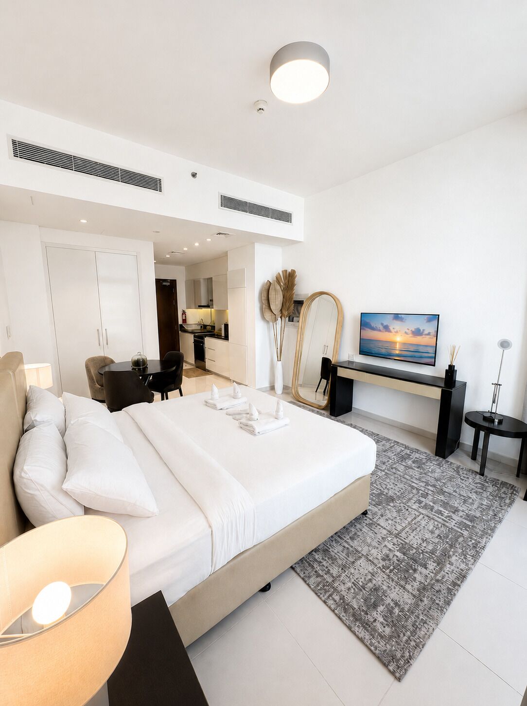 Een moderne hotelkamer met een groot bed, een bureau, een stoel, een televisie en uitzicht op de zonsondergang.