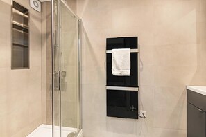 Ein modernes Badezimmer mit Duschkabine aus Glas, einem schwarzen Handtuchhalter und einem weißen Handtuch daran.
