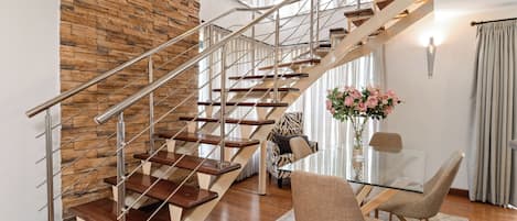 Um interior moderno com escada de madeira, mesa de jantar de vidro e uma cadeira com padrão de zebra.