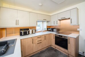A modern kitchen with white cabinets, a built-in oven, a microwave, and a toaster. - Albert Edward House – Modern 2BR Home in Liverpool (Liverpool)