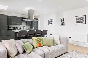 Ein modernes Wohnzimmer mit Sofa, Essbereich und Küche.
