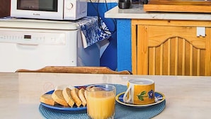 A kitchen with a microwave, a coffee maker, and a breakfast setup on a table.