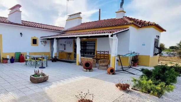 A two-story building with a tiled roof, a covered patio, and outdoor seating.
