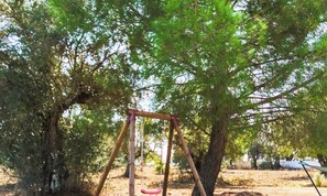 A swing set in a park with trees and a hammock.