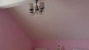 A bedroom with two beds, a dresser, a nightstand, a chandelier, and a patterned rug.