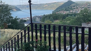 A balcony with a view of a lake, mountains, and a town.