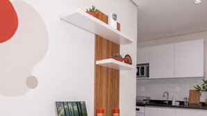 Una cocina moderna con armarios blancos, un escritorio blanco con una computadora portátil y una silla blanca.