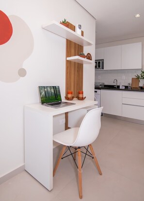 A modern kitchen with white cabinetry, a white desk with a laptop, and a white chair. - Corporate Stays First Living - 506 (Asunción)