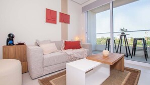 Una sala de estar moderna con sofá, mesa de centro y un balcón con mobiliario exterior.