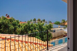 Ein Wohngebiet mit Swimmingpool, einem Haus mit rotem Dach und Blick aufs Meer.