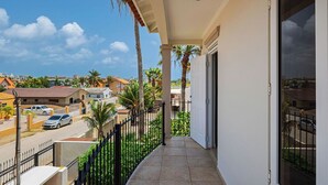 Un balcón con vista a una zona residencial, una calle y un cielo despejado.