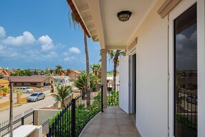 Ein Balkon mit Blick auf ein Wohngebiet, eine Straße und einen klaren Himmel.