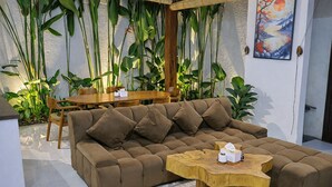 Een moderne woonkamer met een hoekbank, een houten salontafel en een eethoek met een houten tafel en stoelen.