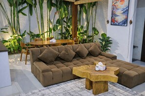 A modern living room with a sectional sofa, wooden coffee table, and a dining area with a wooden table and chairs. - Charming & Serene Bali Villa Minutes from Canggu (Mengwi)