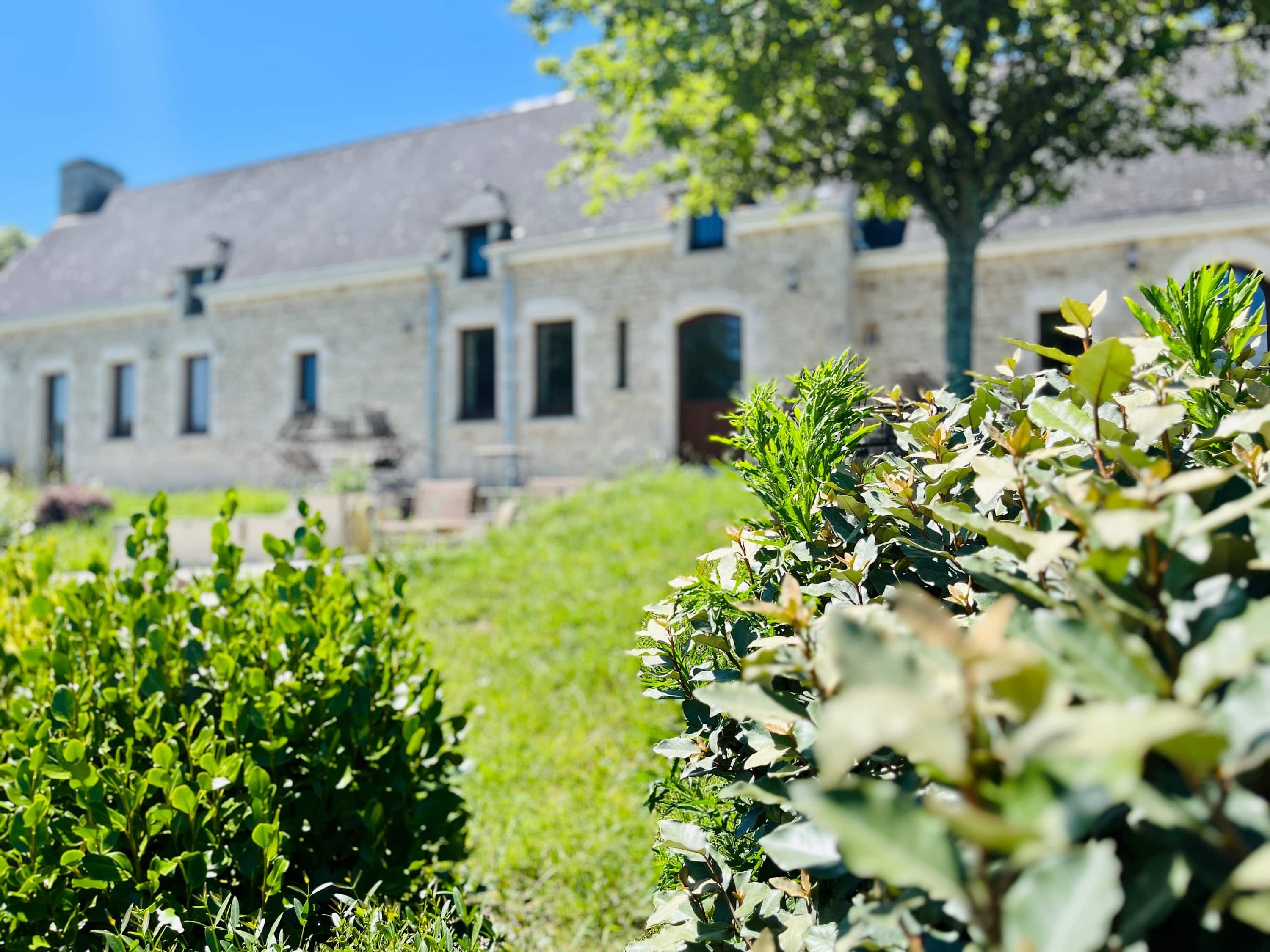 Un bâtiment doté d’une façade en pierre, de nombreuses fenêtres et d’un arbre au premier plan.