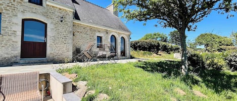 A stone building with a large door, arched windows, and a tree in the yard.