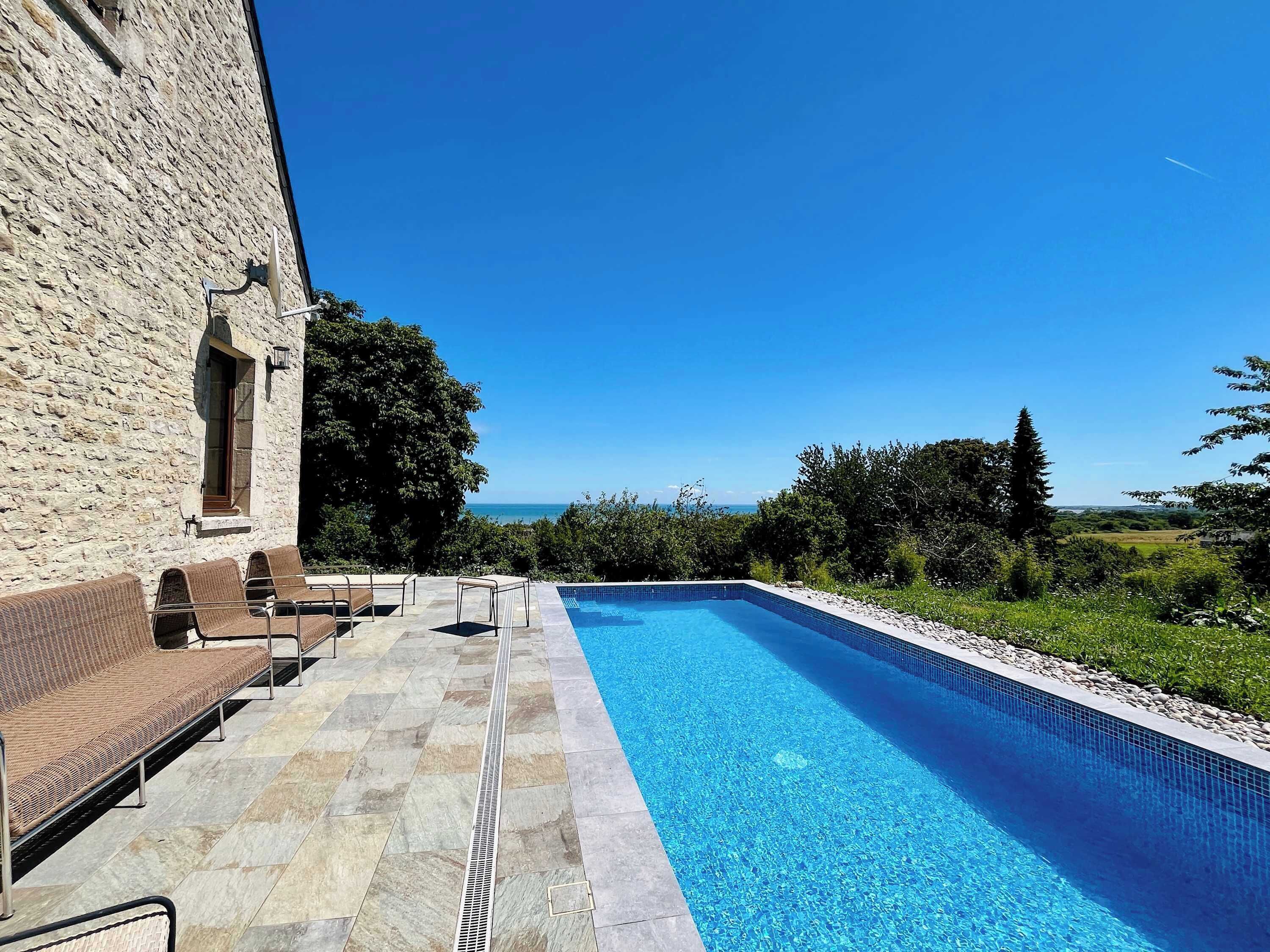 A swimming pool with a stone wall and outdoor seating.