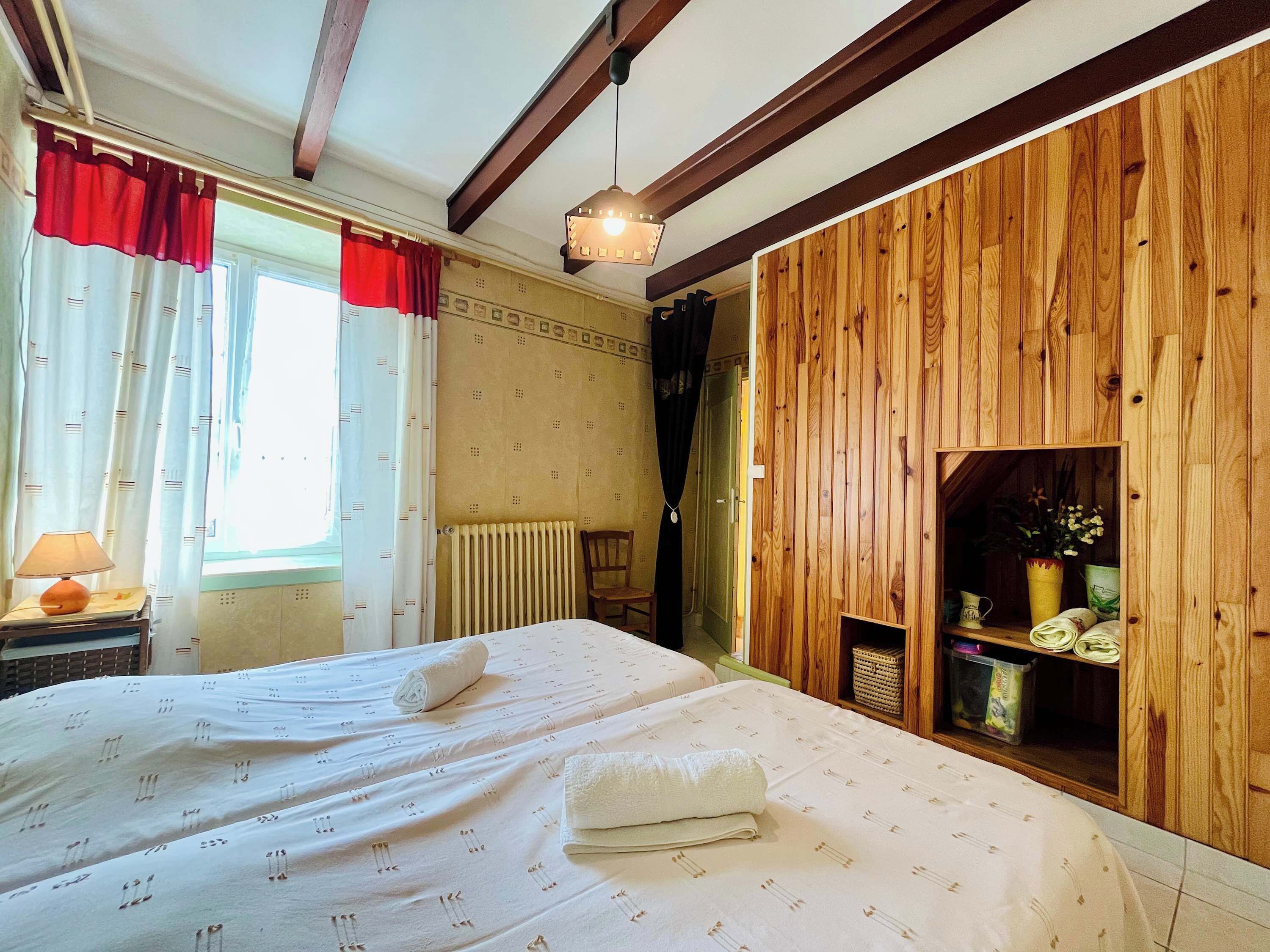 Un dormitorio con cama, radiador, pared de madera y una estantería con objetos.