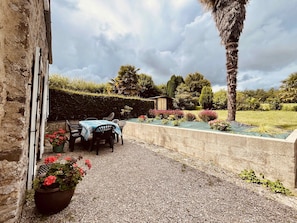 A patio with a table and chairs, surrounded by gravel and potted plants. - Les Palmiers du Cotentin - 1 km from the sea (Aumeville-Lestre)