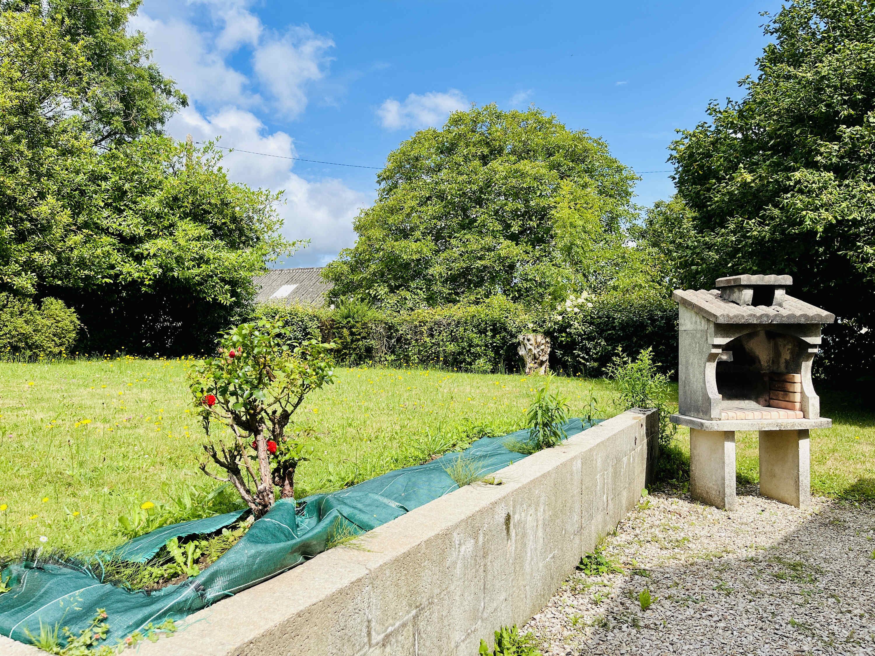 Un jardin agrémenté d’une structure en pierre, d’une pelouse et d’arbres.