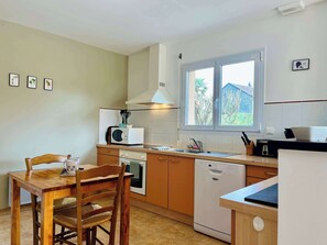 Cocina compacta con comedor, equipada con microondas, horno y lavavajillas.