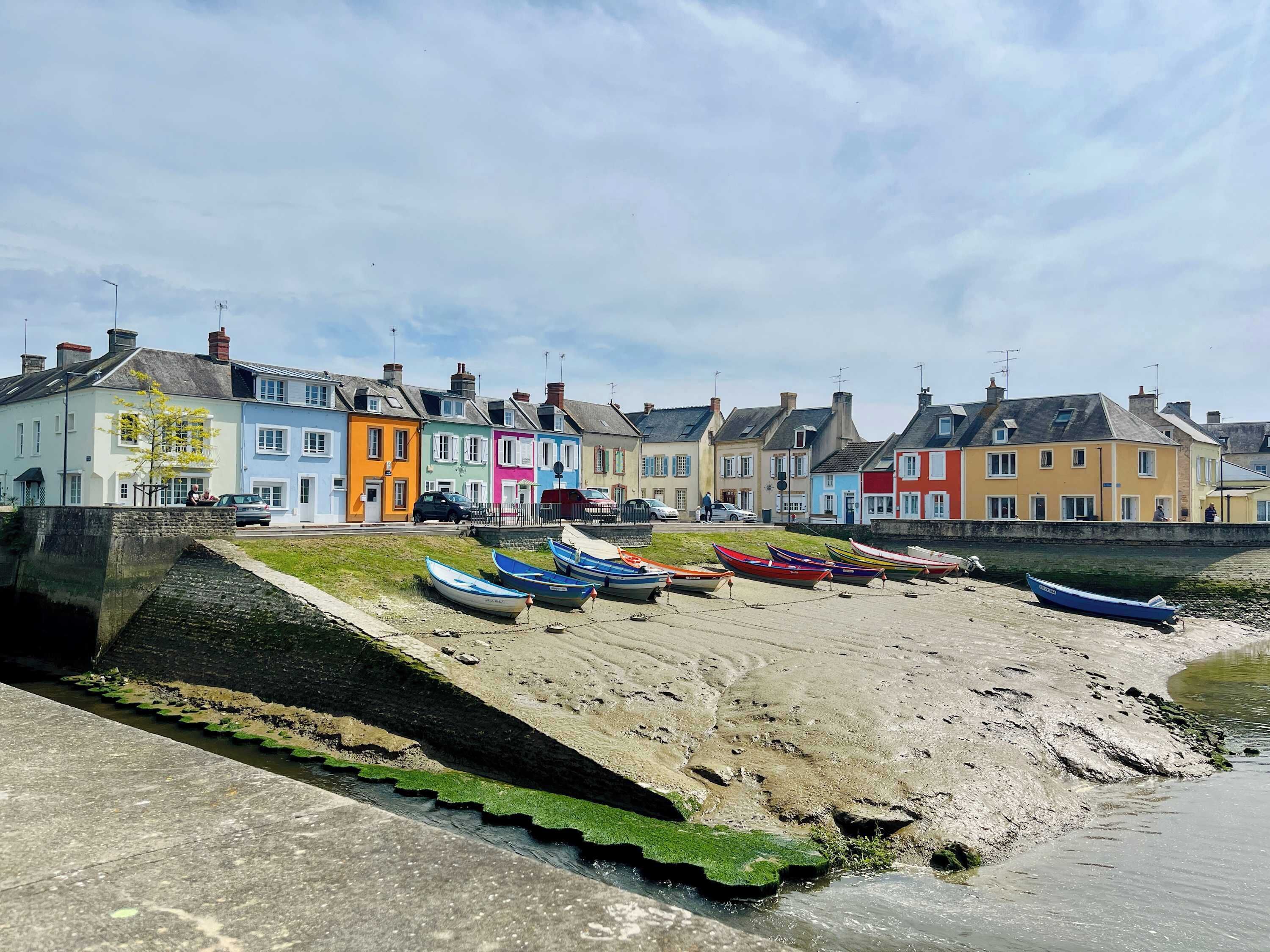 A row of colorful houses by a waterfront with boats docked nearby.