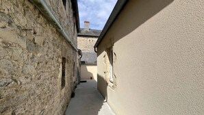A narrow alleyway between buildings with stone walls and a concrete path. - La Maison Bleue, Authentic Fishermans House (Isigny-sur-Mer)