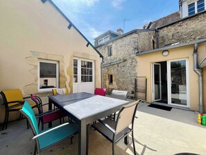 Eine Terrasse im Freien mit Tisch und Stühlen, ein Steinhaus und ein Fenster.