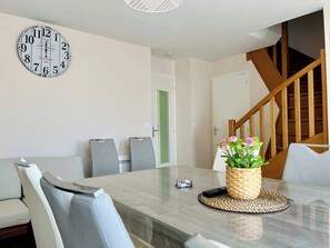 Ein Essbereich mit einem Marmortisch, Stühlen, einer Uhr und einer Treppe.