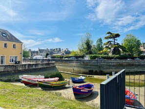 A canal with boats docked, a bridge, and buildings in the background.