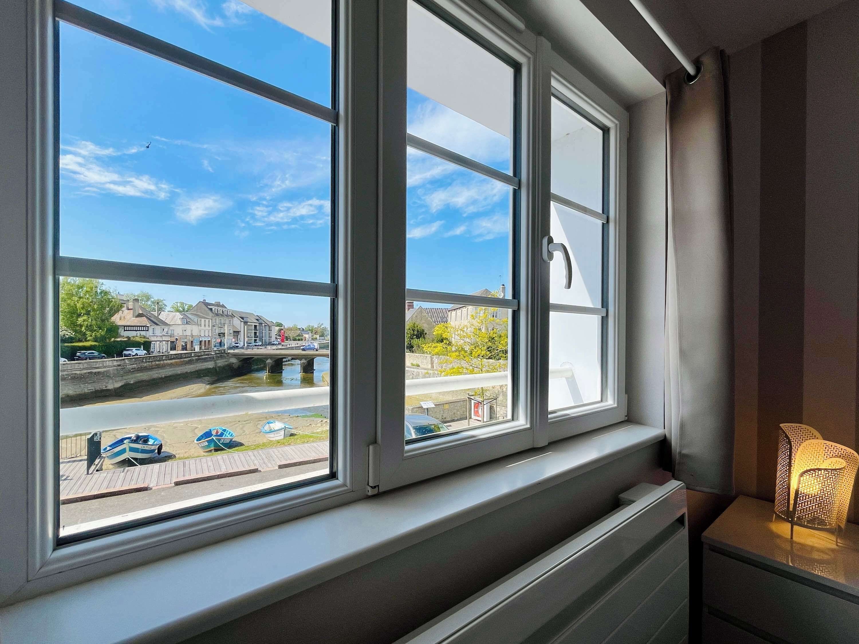 A room with a large window overlooking a river, a bridge, and buildings.