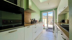 A modern kitchen with a built-in oven, a range hood, and a window above the sink. - La Maison Bleue, Authentic Fishermans House (Isigny-sur-Mer)