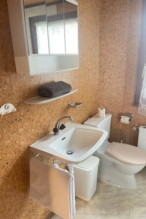 Een badkamer met een wastafel, toilet en spiegel.