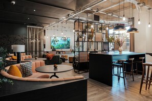 Ein stilvoller Lounge-Bereich mit Sitzgelegenheiten, einer Bar und einem Fernseher, der eine tropische Szenerie zeigt.