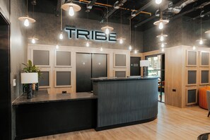 Ein Empfangstresen mit einem Schild mit der Aufschrift 'TRIBE', ein modernes Interieur mit Holzvertäfelung und Pendelleuchten.