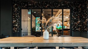 A dining area with a wooden table, chairs, and a vase with dried plants. - Student Only YourTRIBE EC (London)