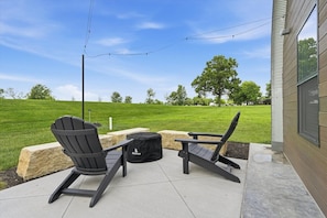 Eine Terrasse im Freien mit zwei Adirondack-Stühlen, einer schwarzen Tasche und einer Lichterkette.