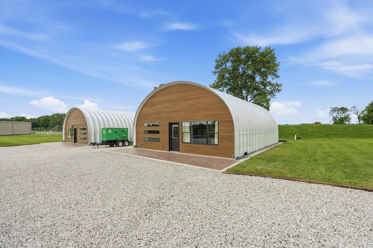 A modern building with a curved roof and a gravel driveway.