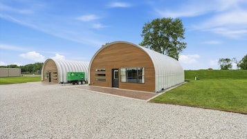 A modern building with a curved roof and a gravel driveway.