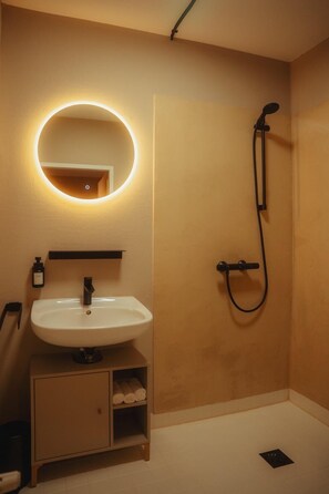 A bathroom with a round mirror, a sink, a shower, and a towel rack. - City Apartment I Free Parking (Bielefeld)