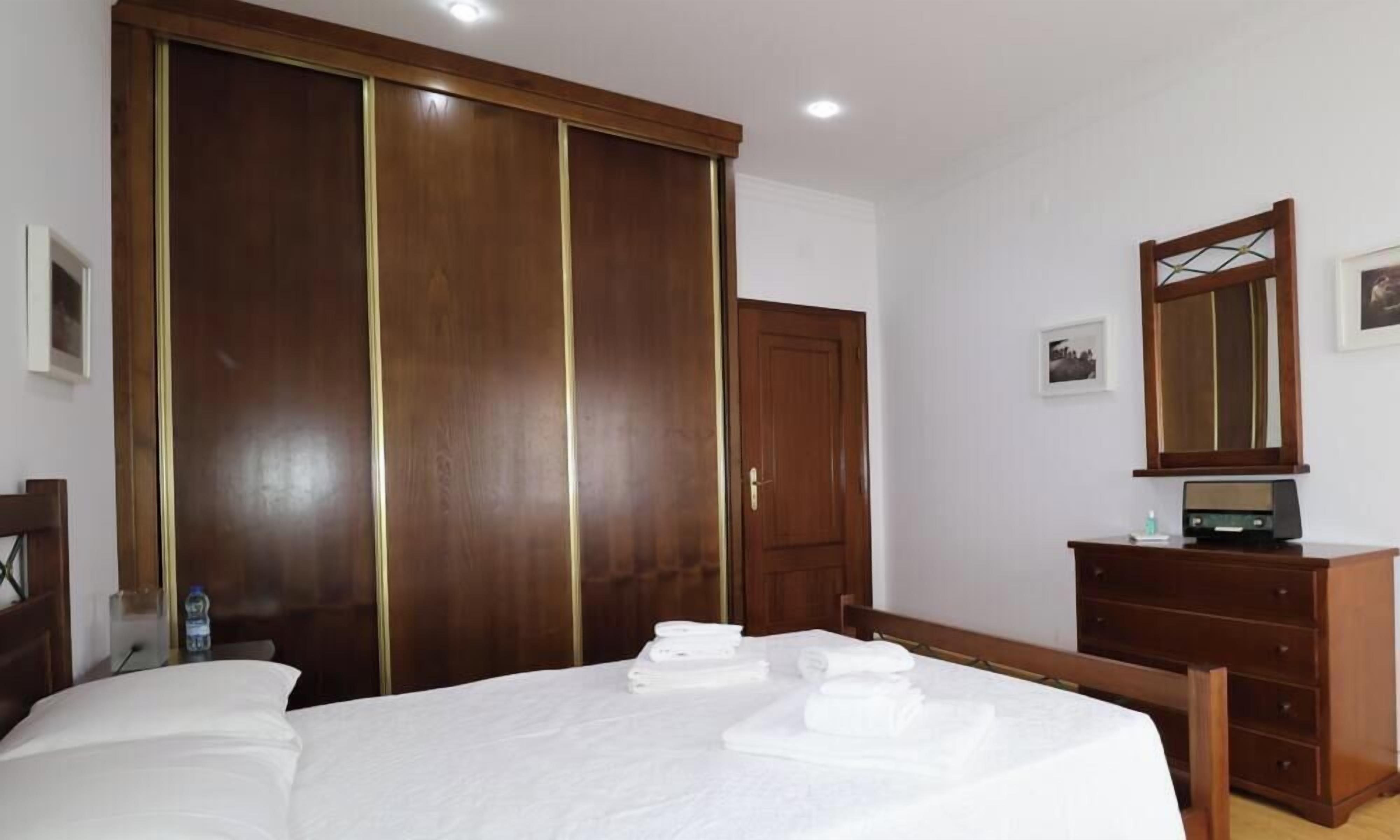 Una habitación de hotel con una cama, un armario de madera, un tocador y un espejo.