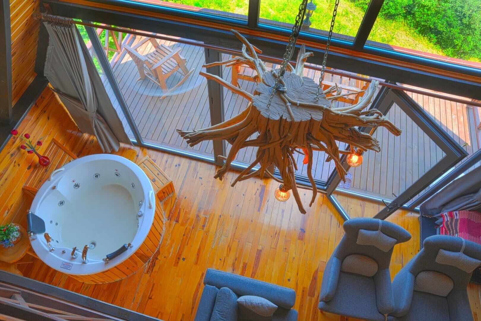 A wooden deck with a hot tub, seating area, and a unique chandelier.