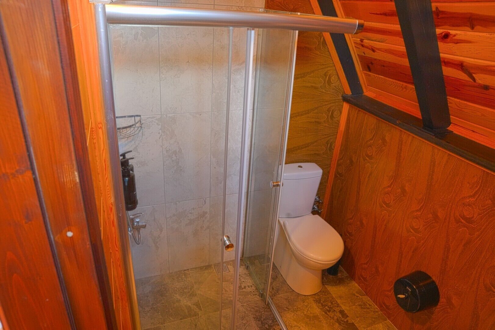 Pieni, erillinen kylpyhuone, jossa on suihku, wc ja pyyheteline.