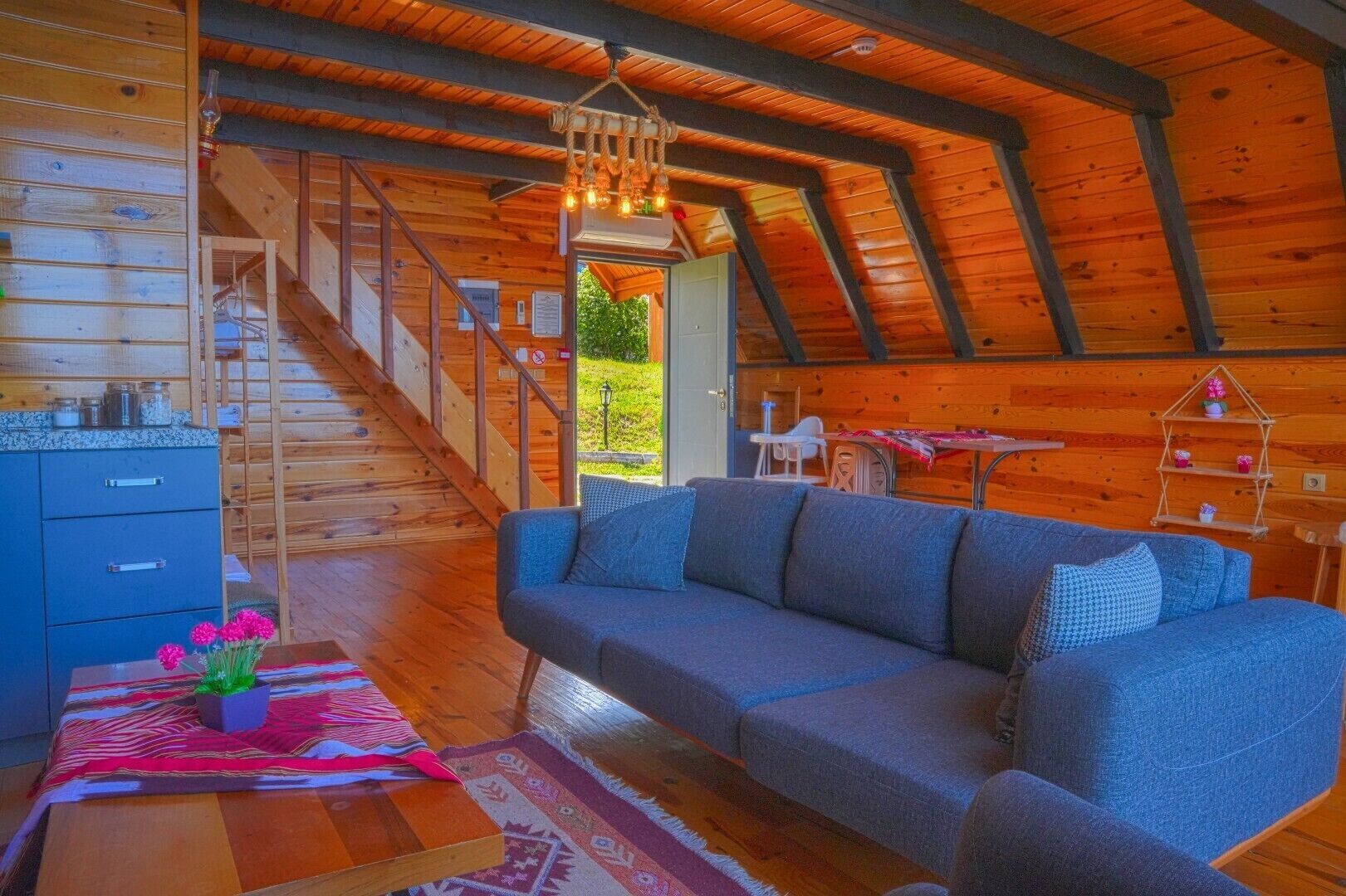 A wooden interior with a sofa, a dining table, and a staircase.
