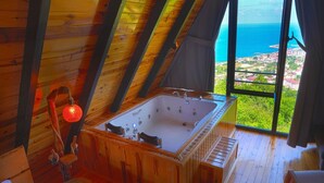 Una cabana de fusta amb una banyera gran, una banca de fusta i vista a l'oceà.