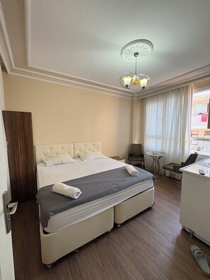 A hotel room with a bed, bedside table, chair, desk, and a view of the outside. - Kerem dalgıç suit (Adana)